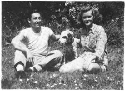 A young couple with a dog sitting on the grass