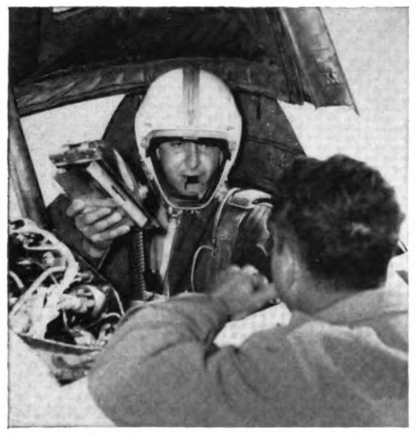 A pilot in an aircraft listening to a man leaning on the plane