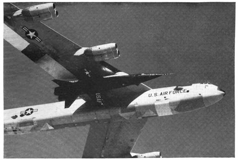 A U. S. Air Force plane in the air with a small plane attached under its wing