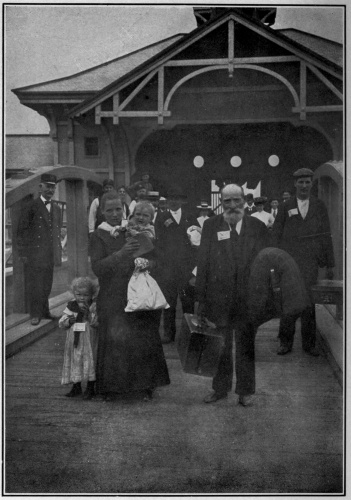 From stereograph copyright&mdash;1904, by Underwood & Underwood, N. Y.
AT THE GATE

With tickets fastened to coats and dresses, the immigrants pass out
through the gate to enter into their new inheritance, and become our
fellow citizens.